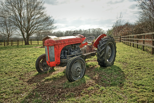 An old farm tractor sits by the side of the road