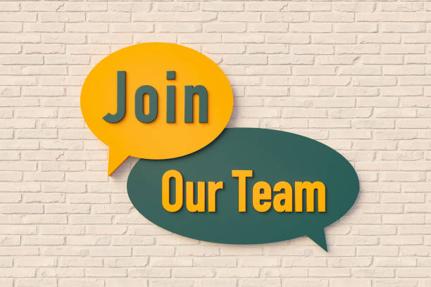 istock Join our team. Sign, speech bubble, text in yellow and dark green against a brick wall. 1387728525