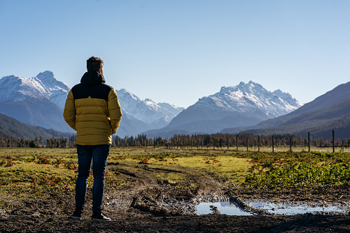 Young man on rural area with amazing view of snowy peak mountains. Glenorchy, South Island of New Zealand