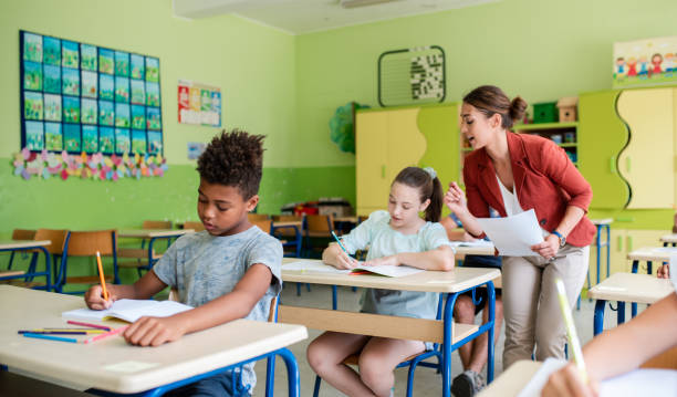 istock Group of students writing on book in classroom 1387738673