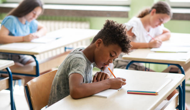 istock Group of students writing on book in classroom 1387739693