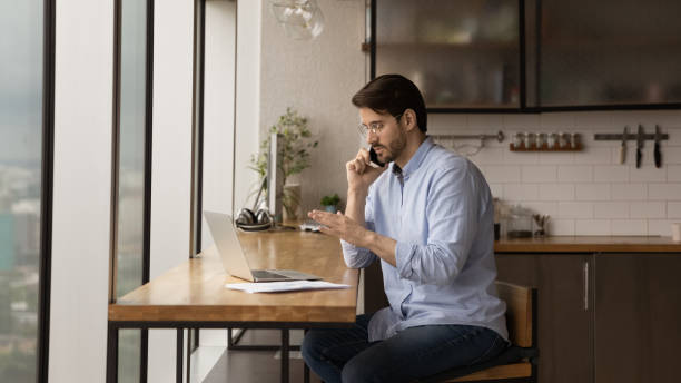 istock Concentrated young businessman multitasking at home office. 1387743655