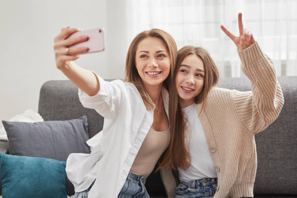istock Smiling mother and daughter taking selfie on smartphone on sofa 1387745851
