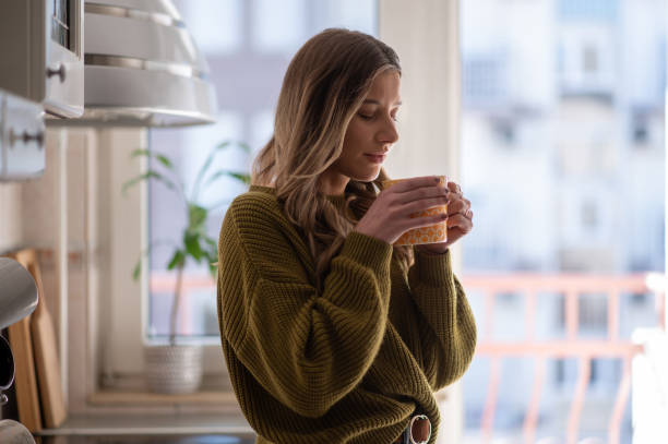 istock Woman standing in the kitchen and drinking cup of tea 1387746219