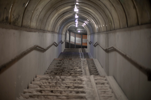 Staircase in snow. Pedestrian crossing across street. Lifting tunnel. Steps up. Artificial light.