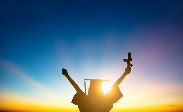 The silhouette of Student Celebrating Graduation watching the sunlight stock photo
