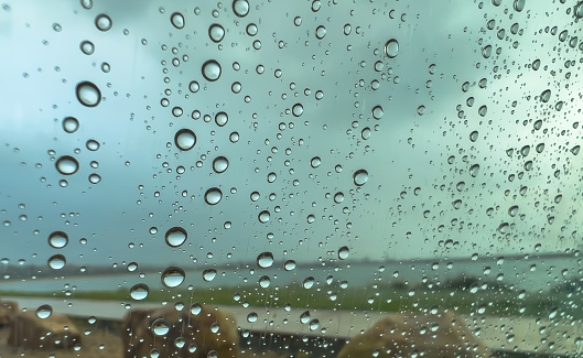 Rain drops on window glass background of heavy rainy day.