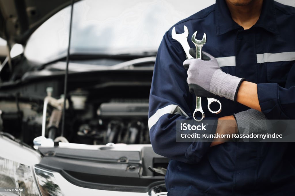 Hand of car mechanic with wrench. Auto repair garage. mechanic works on the engine of the car in the garage. Repair service. Concept of car inspection service and car repair service. Auto Repair Shop Stock Photo