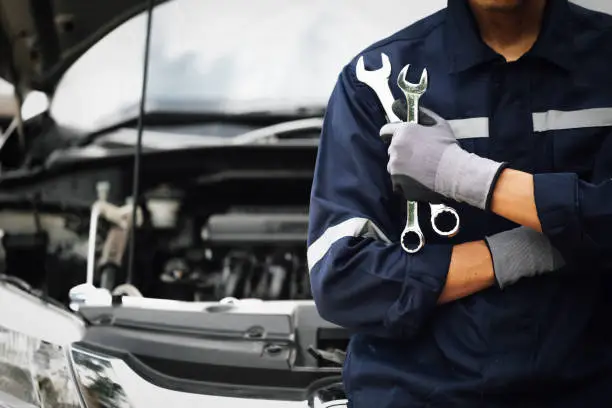 Photo of Hand of car mechanic with wrench. Auto repair garage. mechanic works on the engine of the car in the garage. Repair service. Concept of car inspection service and car repair service.