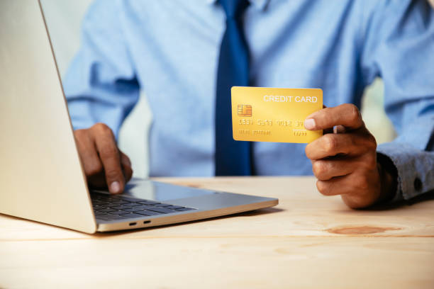 istock Man holding credit card and using laptop computer. Online shopping concept. 1387764464