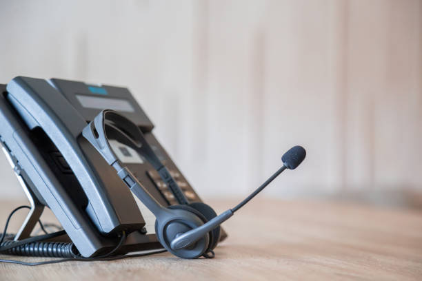 istock Communication support, call center and customer service help desk. VOIP headset on telephone keyboard. 1387764476