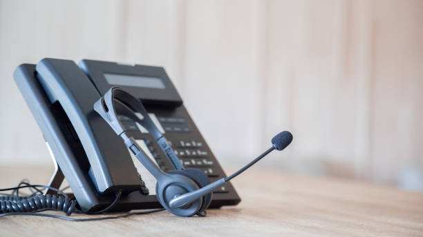 istock Communication support, call center and customer service help desk. VOIP headset on telephone keyboard. 1387764477