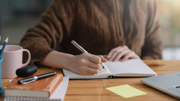 istock Close up of woman hand using pen taking notes in office. 1387770616