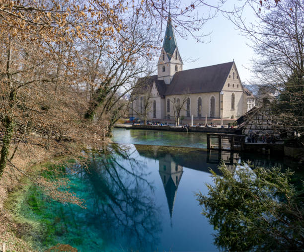 istock Beautiful and deep little lake with source on the bottom and nice green and blue colours called Blautopf in Germany with a monastery in the background and reflection in the lake 1387774520