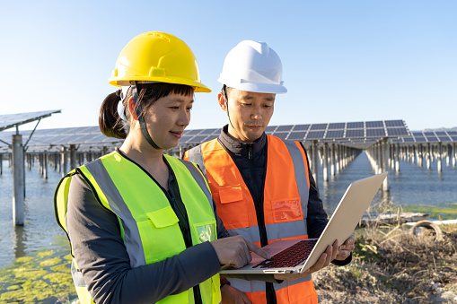Primer plano de ingenieros masculinos y femeninos discutiendo el trabajo en la planta de energía solar photo