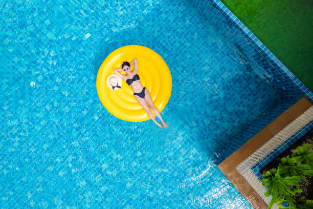 vue de dessus d’une jeune femme asiatique en bikini sur l’anneau gonflable jaune dans la piscine de la villa privée. concept de vacances d’été - outdoor chair furniture travel vacations photos et images de collection