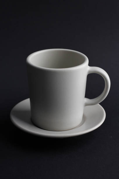 istock White blank ceramic mug and white saucer on black background. 1387779563