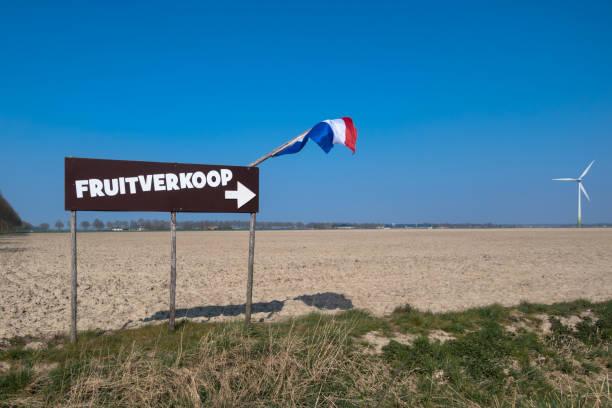 Fruit sale plate with Dutch flag A brown sign with the Dutch flag in a dry field along the road in Flevoland with a windmill in the background refers to the sale of fruit. local products stock pictures, royalty-free photos & images