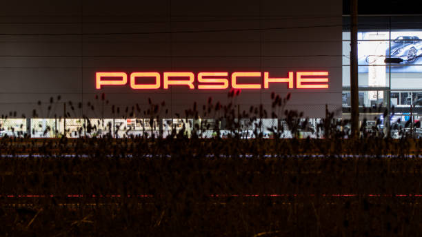 The Porsche text logo on the side of a dealership building at night. stock photo