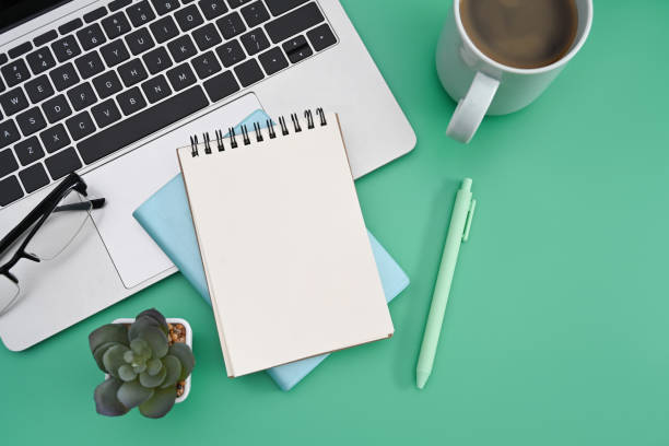 istock Top view notepad, laptop computer, coffee cup and cactus on green background. 1387782018