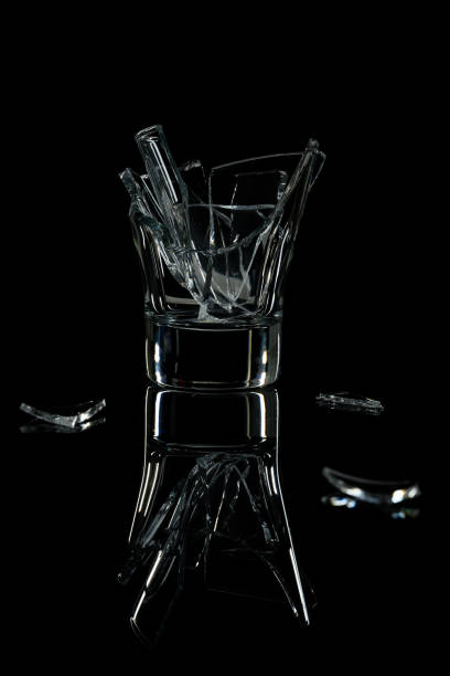 A broken cocktail glass on a black mirror surface.