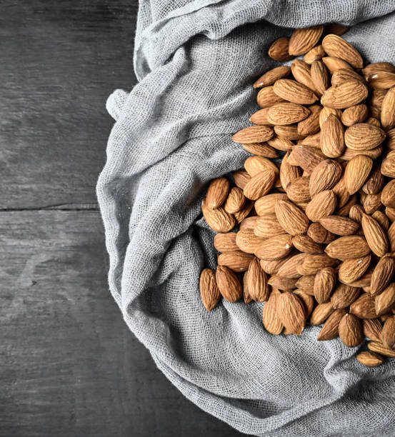 istock Almonds in white porcelain bowl on dark background. Almond concept with copyspace. 1387785039