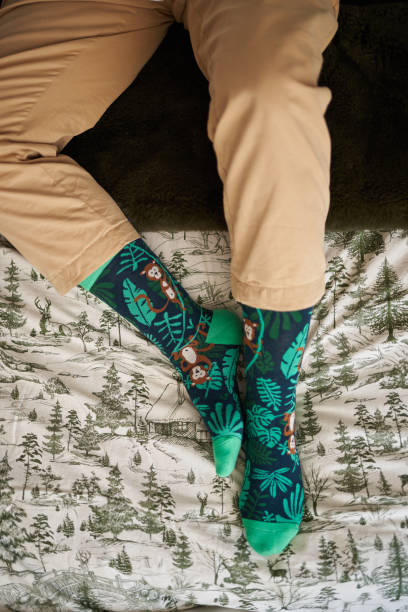 istock Top view of some feet with funny monkey socks on a bed 1387786470