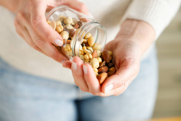 istock Nuts spilling from jar in woman's hand 1387793564