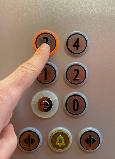 istock Man's hand pressing the button to go up to the third floor of an elevator. 1387794602