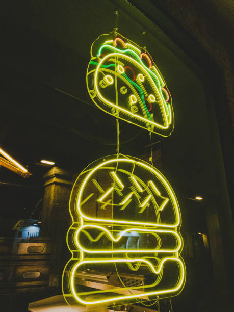 Yellow neon light in a shop window drawing a hamburger and a piece of pizza.
