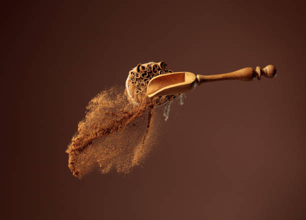 la canela en polvo se vierte fuera de la cuchara de madera. - ground cinnamon fotografías e imágenes de stock