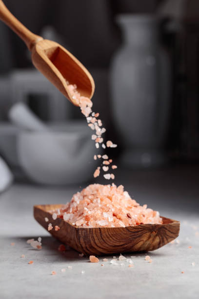 istock Pink salt is poured into a small wooden bowl. 1387796748