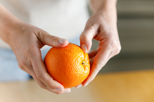 La mano de la mujer pelando una naranja photo