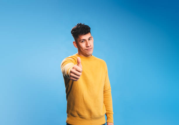 istock Positive man showing thumb up while standing on isolated background. 1387798274