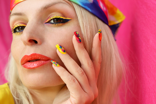 A model in a headscarf with a multicolored manicure and makeup.