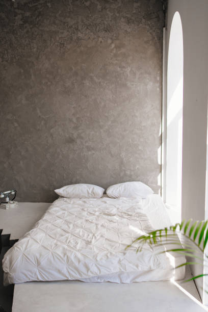istock a bed in a room with grey walls and large windows. 1387804603