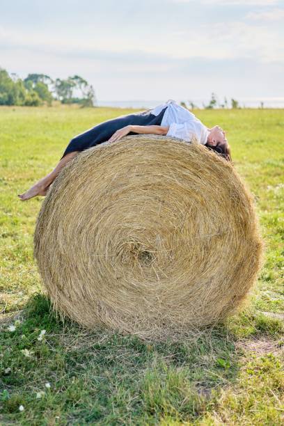 istock A beautiful young woman lying on back on a haystack on a green field. 1387804666