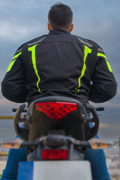 close-up - vista de trás de um cavaleiro anônimo vestido com jaqueta de motoqueiro olhando o horizonte do mar ao pôr do sol - motorcycle mirror biker glove - fotografias e filmes do acervo