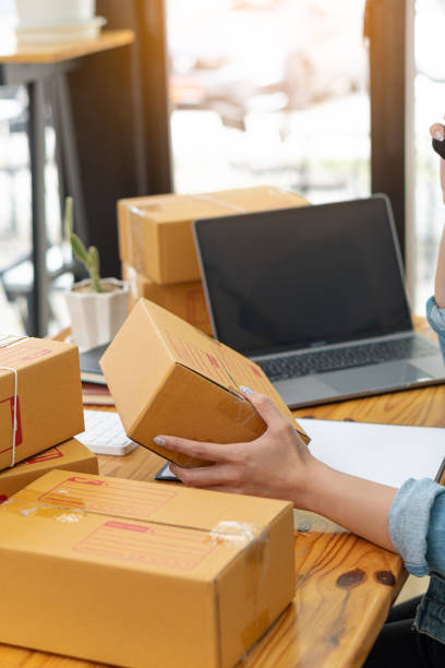 istock Asians working with laptop computers checking numbers online, selling start-ups, small business owners, e-commerce concepts, young women pack items into boxes to ship to customers. 1387807764