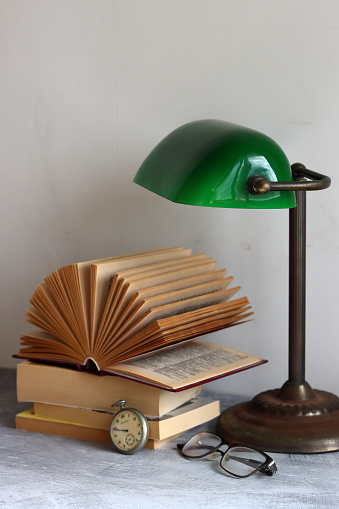 Simple composition still life with vintage lamp and book on a desk. Retro styled objects close up photo.