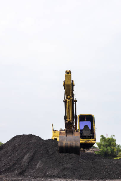 istock Vertical low view in front of an old yellow backhoe parked on a mound. 1387809274