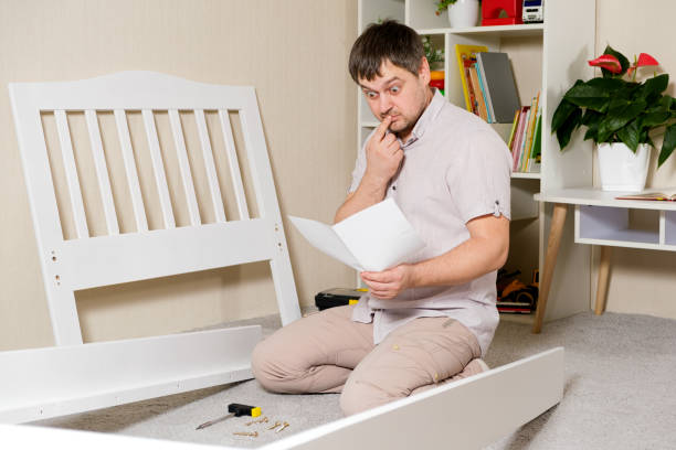 istock A man with instructions for assembling furniture is going to assemble a children's white wooden crib in a children's bedroom. 1387811086