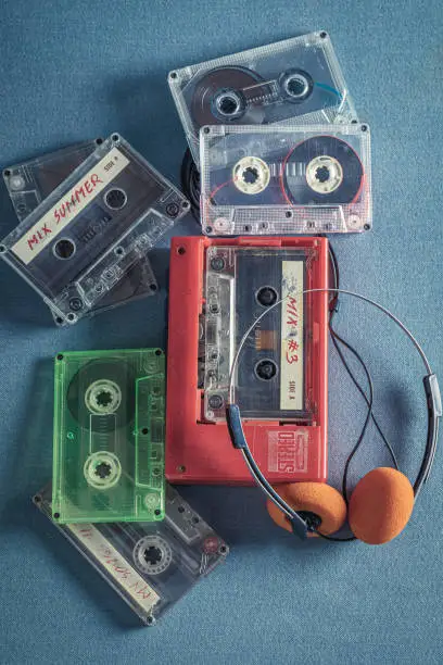 Vintage audio cassette as a symbol of 90's music. Cassette audio tapes with a red player and headphones.