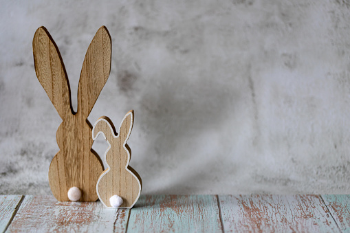 Two wooden Easter bunnies on a light concrete background, Easter greeting card, copy cpace.