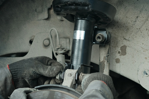 Replacement of the front strut of the shock absorber. The mechanic fixes the position of the shock absorber strut with a mounting bolt.