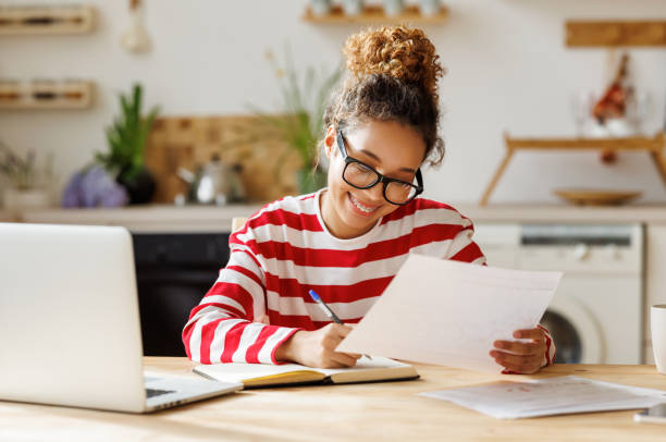 istock Young happy african american woman remote worker analyzing financial report while working remotely at home 1387813791