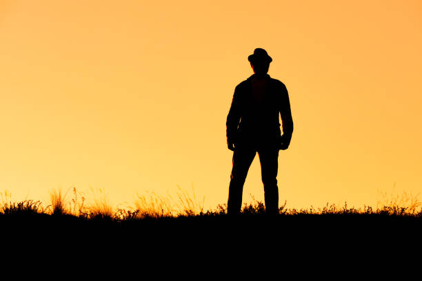istock silhouette of a standing man in a hat on an orange background 1387814680