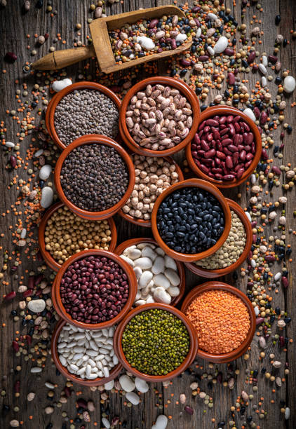 istock Assorted legumes in round clay containers on rustic wooden background and serving scoop 1387814741