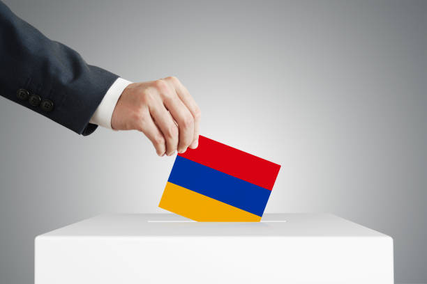 istock Man putting a ballot into a voting box. 1387814754