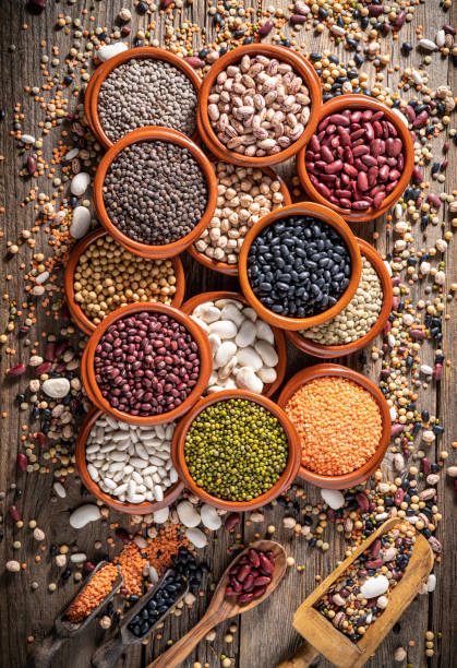 istock Assorted legumes in round clay containers on rustic wooden background and serving scoop 1387814878